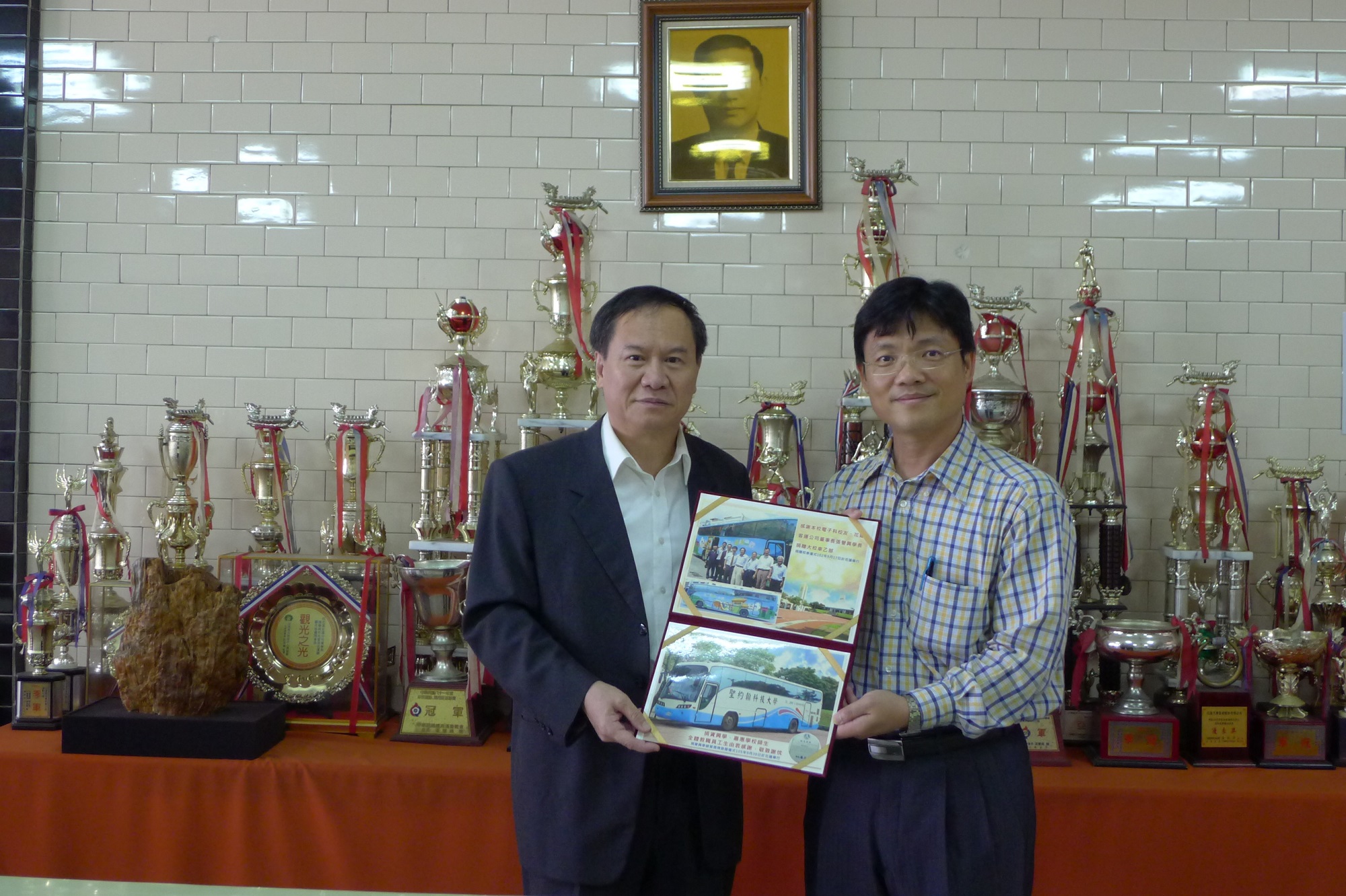 張譽興董事長曾捐贈一部遊覽車供聖約大做為教職員工交通車，艾和昌校長（右）特別致贈感謝狀