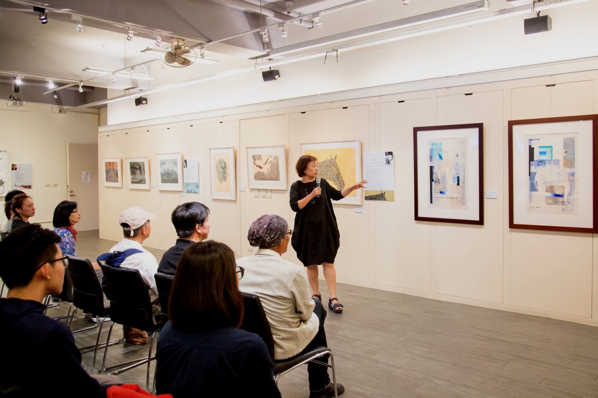 台灣版畫家劉裕芳老師正在解說作品，每幅作品姿態互異、內涵豐富，無形中推動了藝術與人文的交流