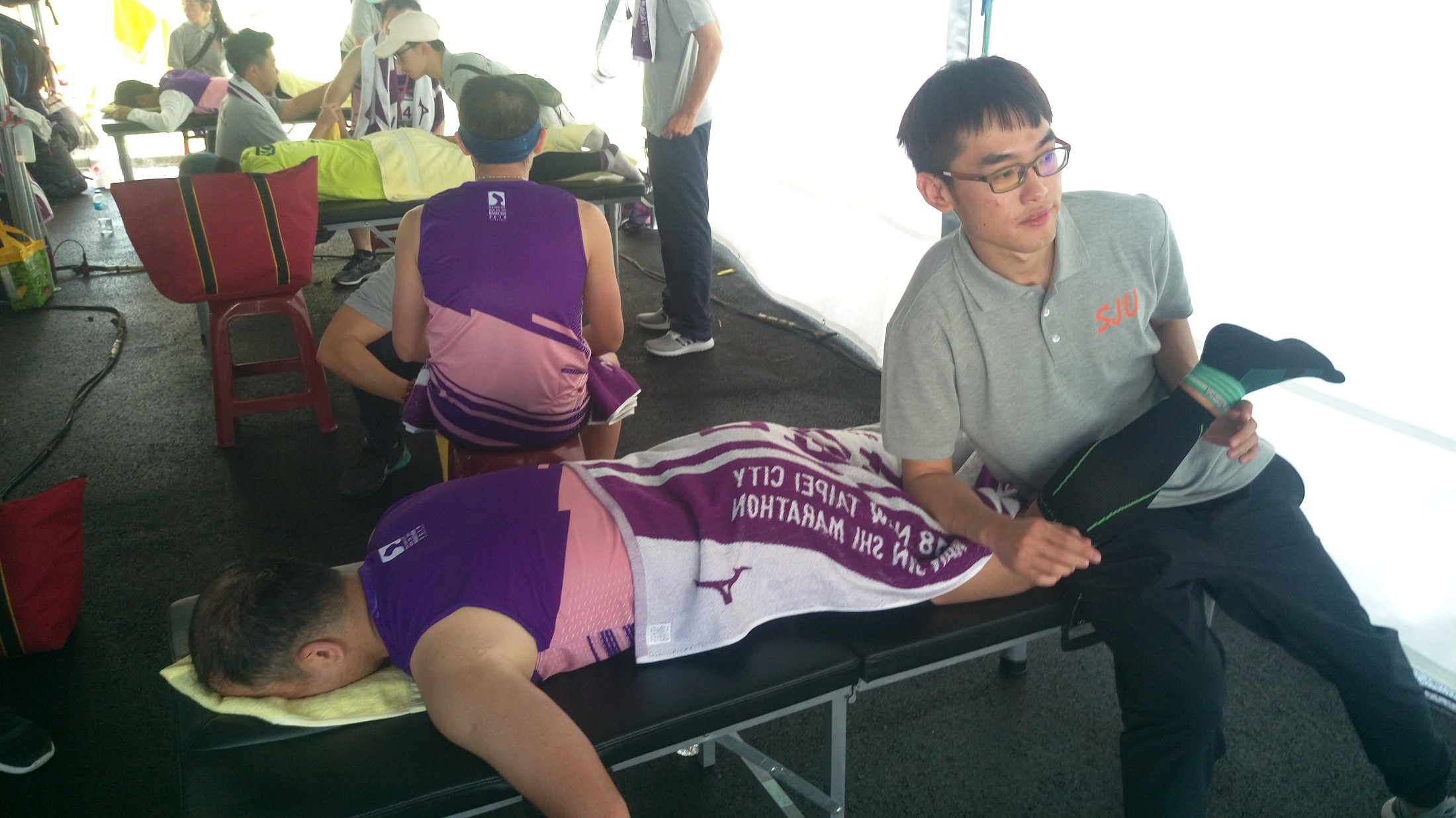 休健三真潘建勛同學（右）協助完賽的跑者進行下肢運動舒壓按摩服務