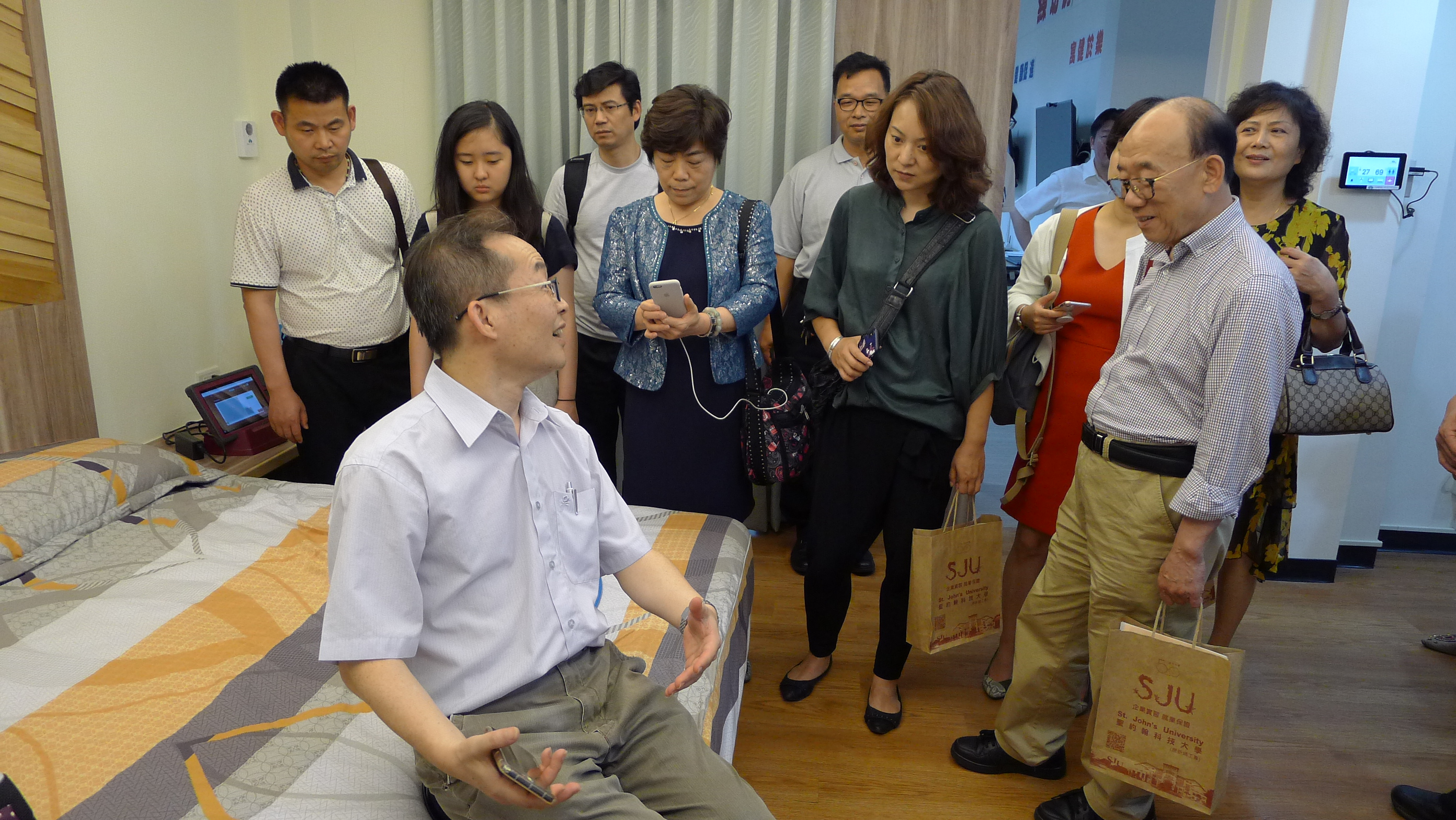 上海養老專委會一行人對老人生活模擬教室所使用的移位板設備覺得新鮮與好奇，紛紛實地體驗利用輔具移位的技巧