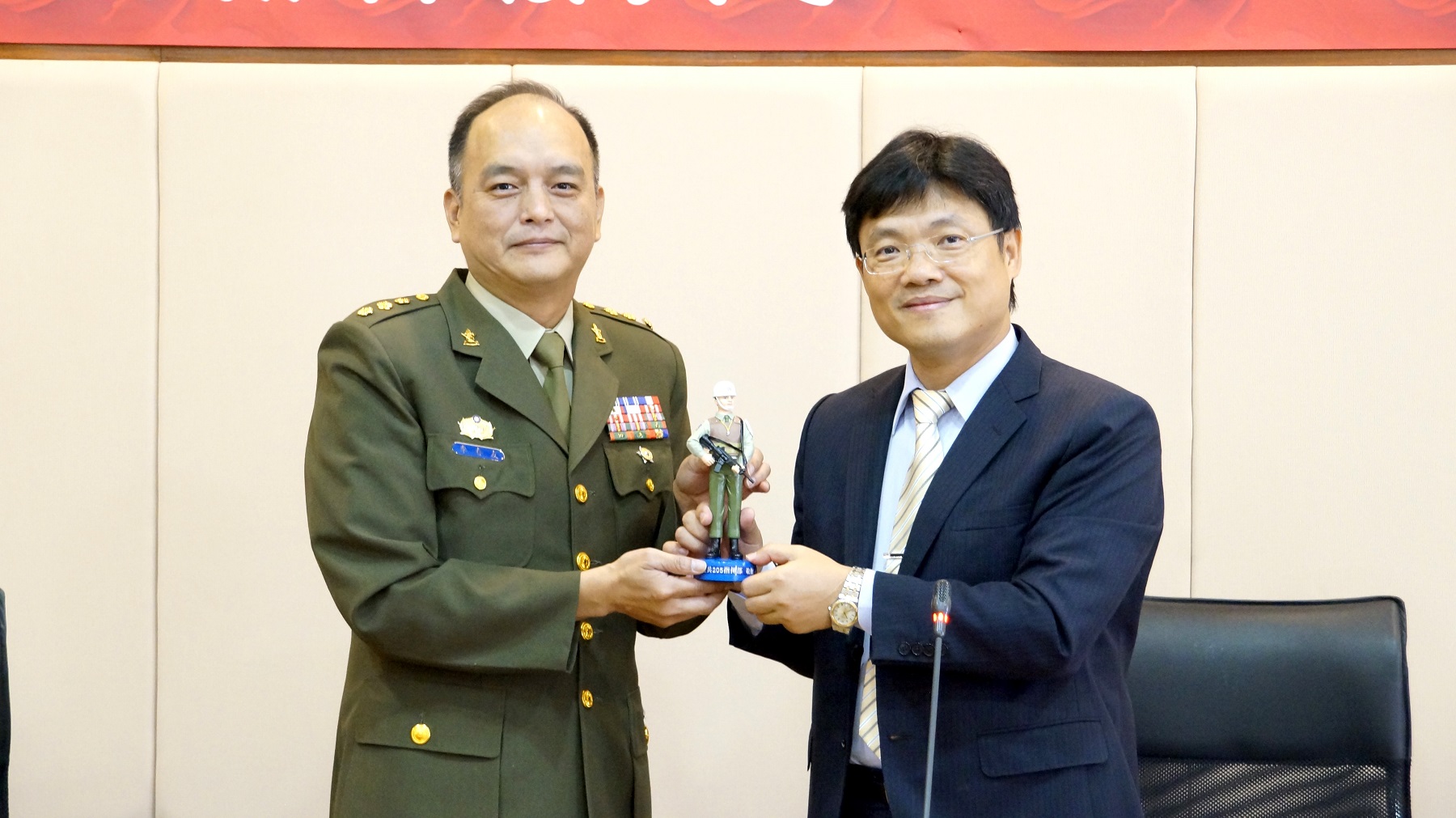 憲兵205指揮部上校李春友（左）致贈憲兵公仔紀念品給艾和昌校長（右）