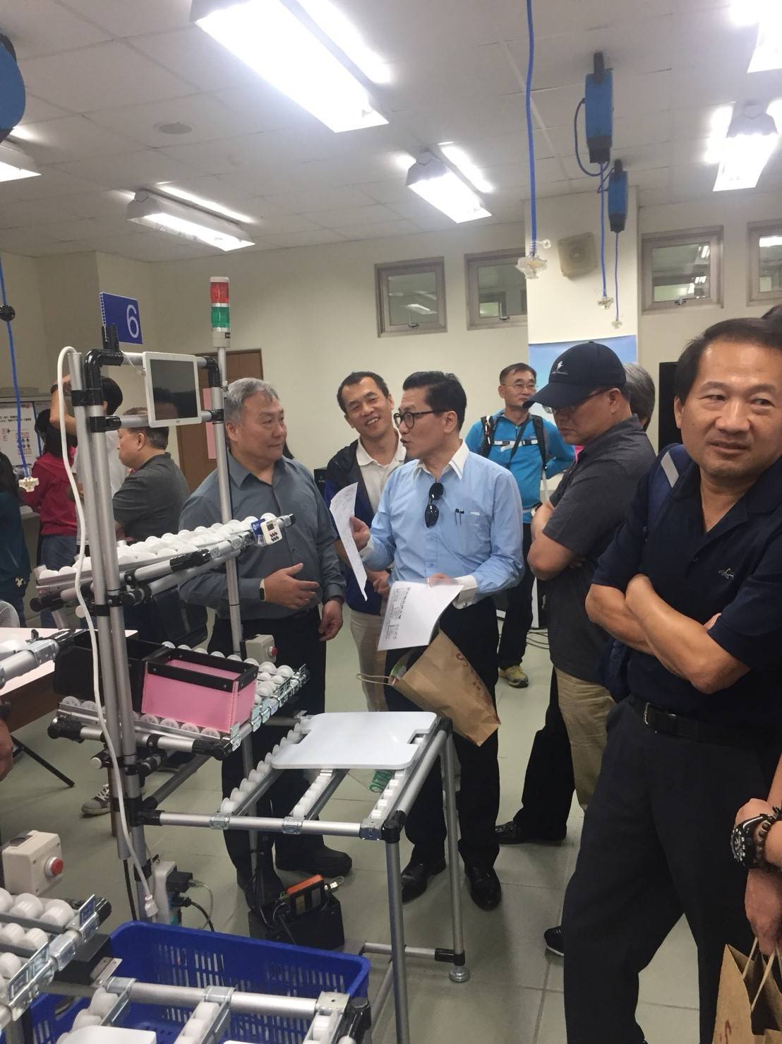 工管系主任黃國男（左三）向從事電子業的陳祖望學長（左五）簡介精實生產線流程。
