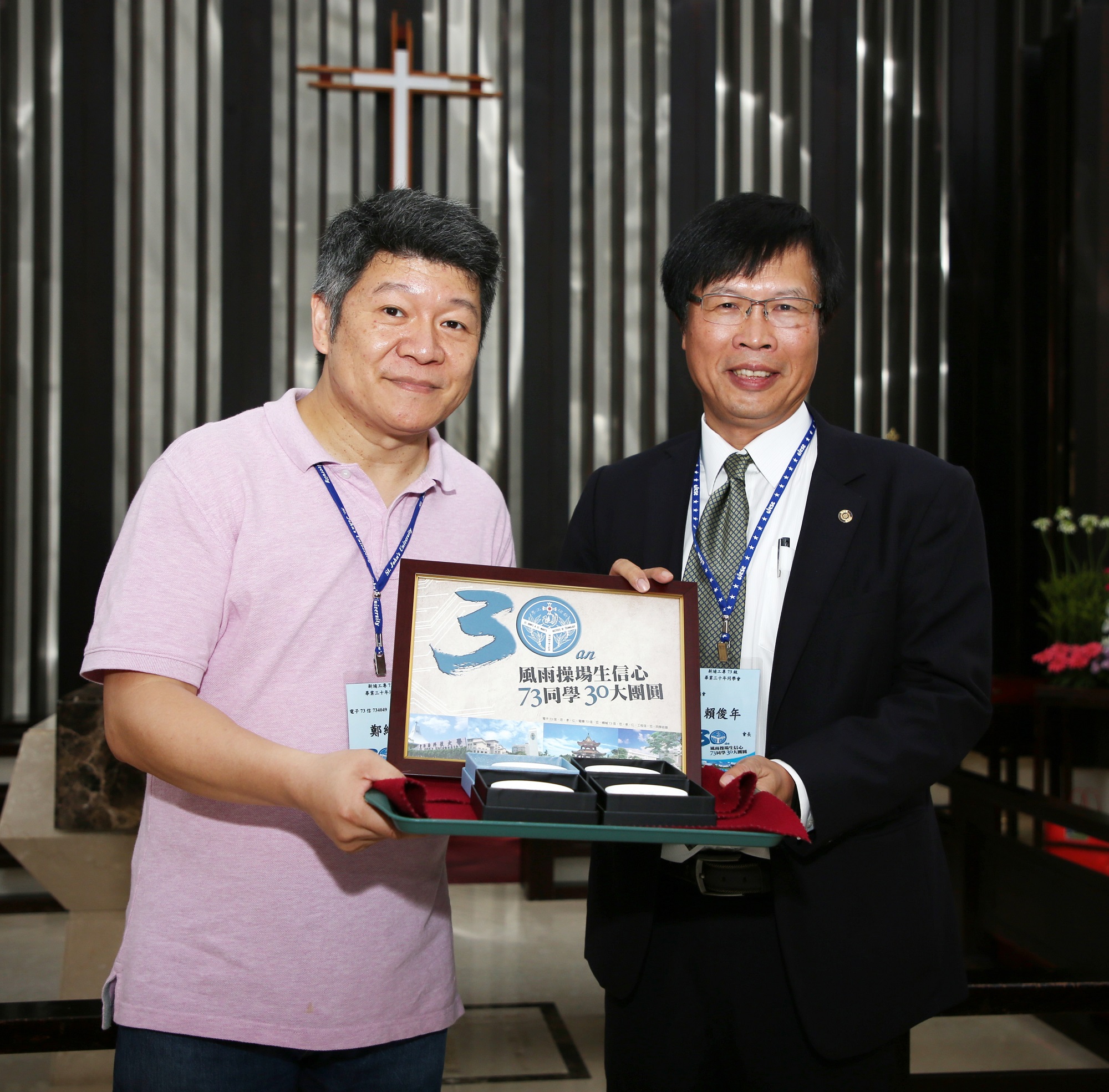 本屆活動主辦人、電子科信班鄭維浩（左）贈送73屆畢業30週年回娘家活動紀念品給校友會賴俊年會長（右）