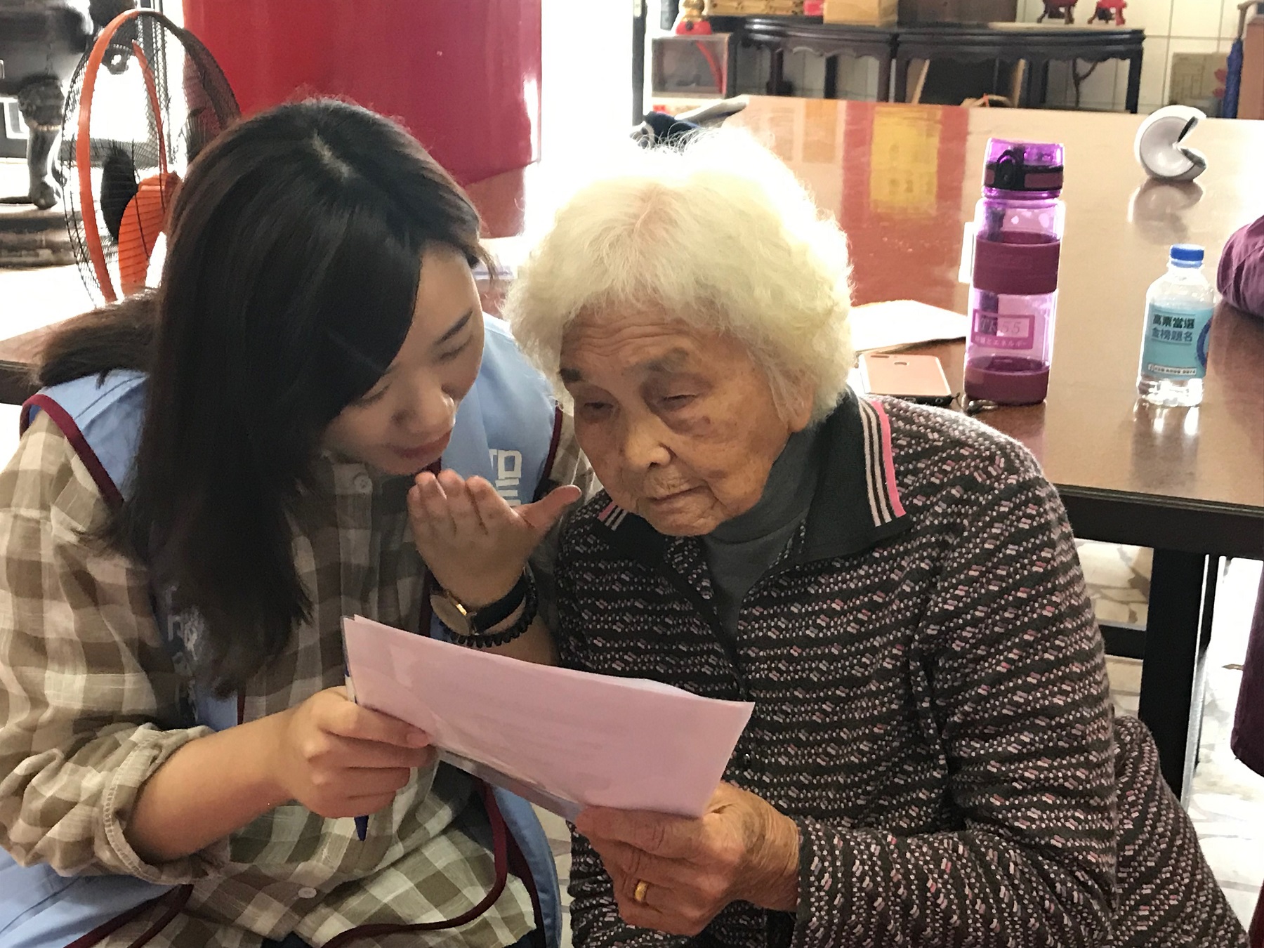 老服系江怡萱同學（左）訪問高齡94歲的李阿嬤（右），阿嬤表示，每週四都很期待學生到慈玄宮陪他們做運動、玩遊戲、吃午餐，跟學生互動讓她覺得心情很快樂