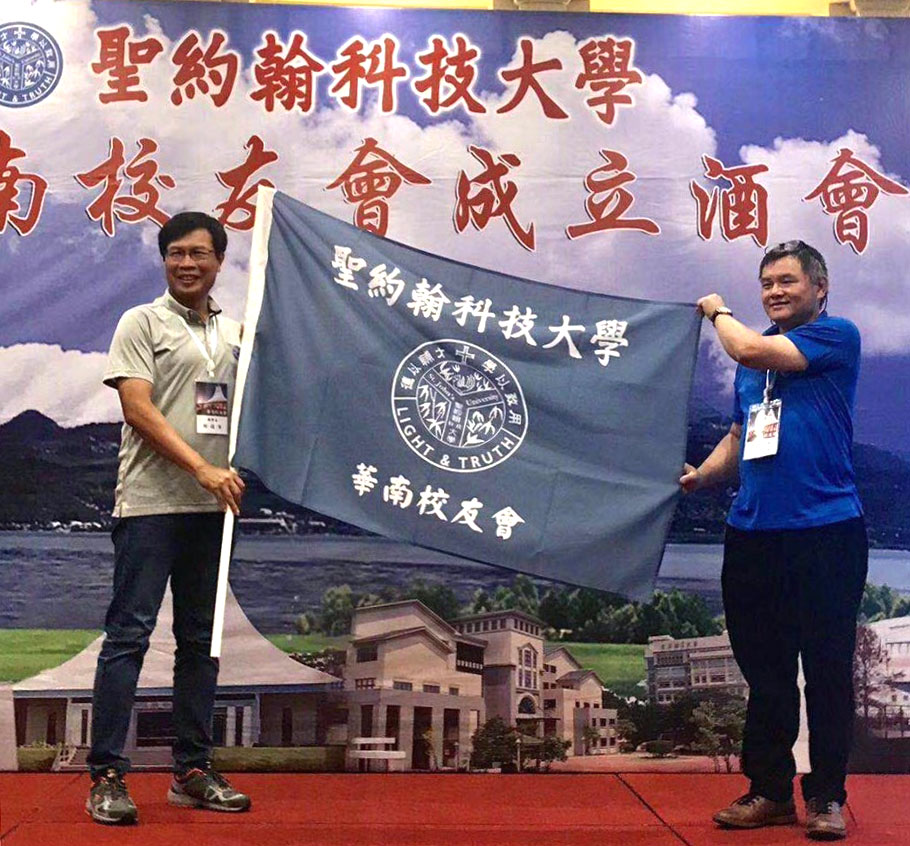 校友總會賴俊年總會長（左）授旗給華南校友會游森林會長（左二）