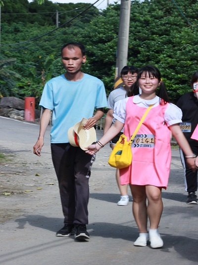 裝扮成「龍貓」電影小梅模樣的創意設計系王若伃同學（右）接手引導視障同學邱詠旌（左）安全地跑完全程。