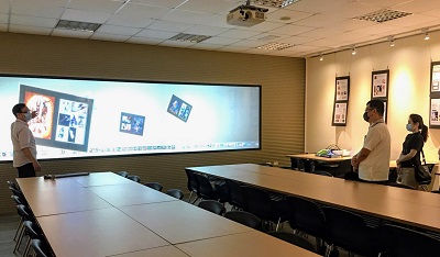 多媒體設計系陳國雄主任（左一）示範互動媒體設計實驗室巨幅電視牆之操作方式。