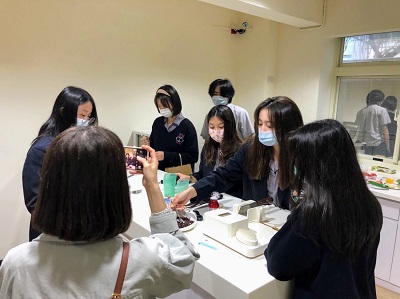 淡江高中同學對廚房輔具感到興趣，練習使用輔助湯匙夾取食物。