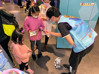  洪大鈞同學（右一）指導小朋友操作智慧機器人，看到小朋友們的笑容，讓他覺得辛苦研究都是值得的。