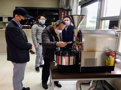 游啟明董事長（右二）仔細觀看休閒運動與健康管理系 築夢花園實習咖啡廳裏面的咖啡烘焙機。