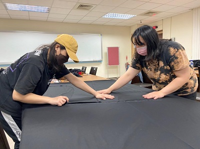 學員彼此分工合作測量與標記布料尺寸，以利後續剪裁。