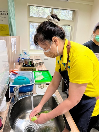 台灣關懷弱勢家庭協會鄭賢美理事長認真執行備餐後的清洗流程。