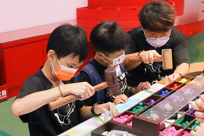 兒童夏令營總召黃啓政同學（右一）向小朋友示範如何製作彩色筆。