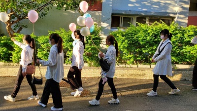 樂齡系同學穿著白色襯衫、繫著學校的領帶，手持氣球，開心參加成年禮儀式。